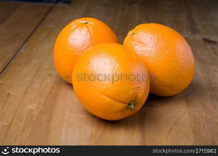 Three oranges on a wooden table