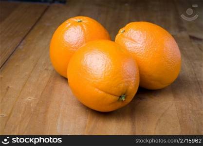 Three oranges on a wooden table