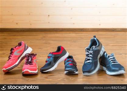 Three pairs of sports sneakers on a wooden floor close-up