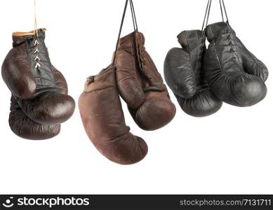 three pairs of very old vintage leather boxing gloves hanging on laces, sports equipment isolated on white background