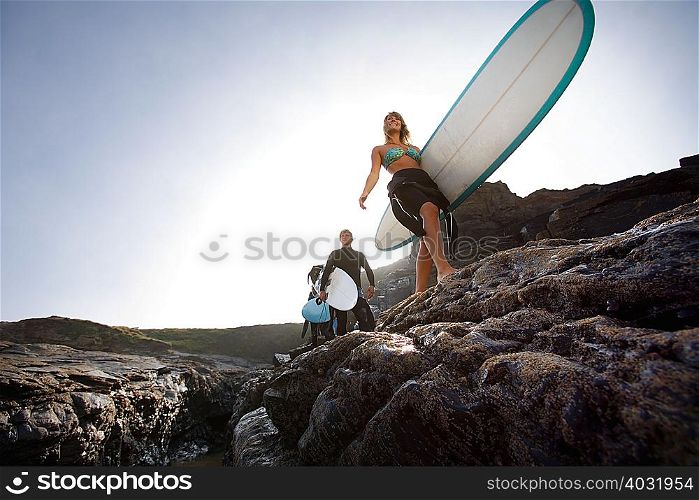 Three people carrying surfboards