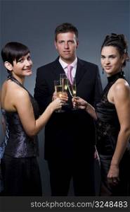 Three people drinking champagne on a party.