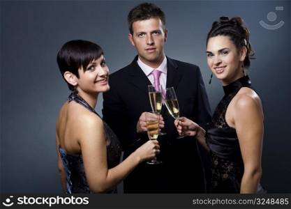 Three people drinking champagne on a party.