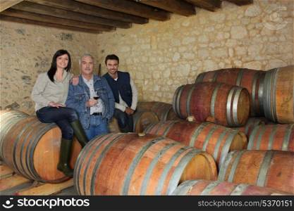 three people drinking wine in a cellar