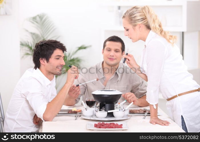 Three people enjoying fondue