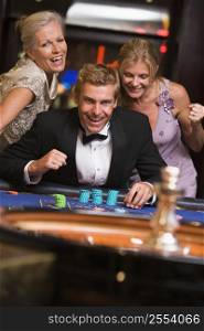 Three people in casino playing roulette smiling (selective focus)