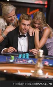 Three people in casino playing roulette smiling (selective focus)