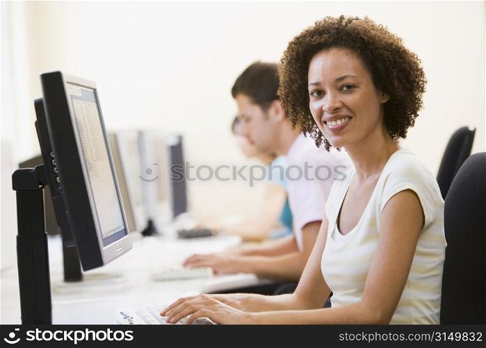 Three people in computer room typing and smiling