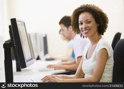 Three people in computer room typing and smiling