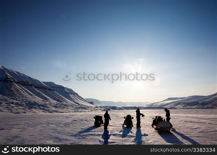 Three people on a winter snowmobile adventure in Svalbard, Norway