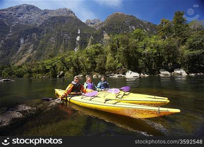 Three people paddling kayaks in mountain lake