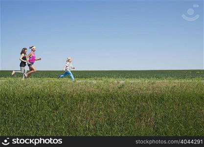 Three people running through field