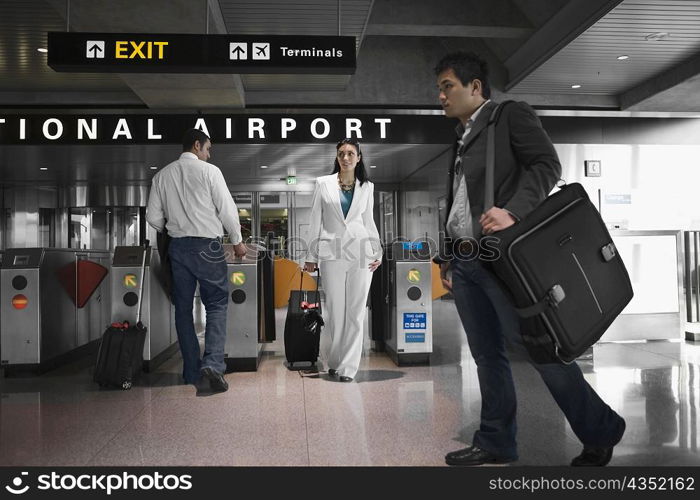 Three people walking at an airport