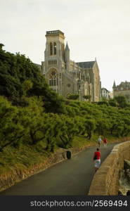 Three people walking on the road, Eglise Sainte Eugenie, Biarritz, France