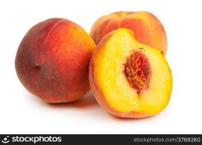 Three perfect, ripe peaches with a half and slices isolated on a white background.