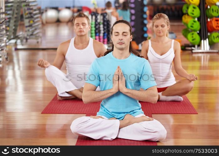 Three persons sit in a lotus pose