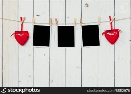 three photo frame blank and red heart hanging on white wood background with space