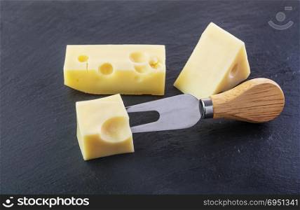 Three pieces of cheese on a black stone slate plate