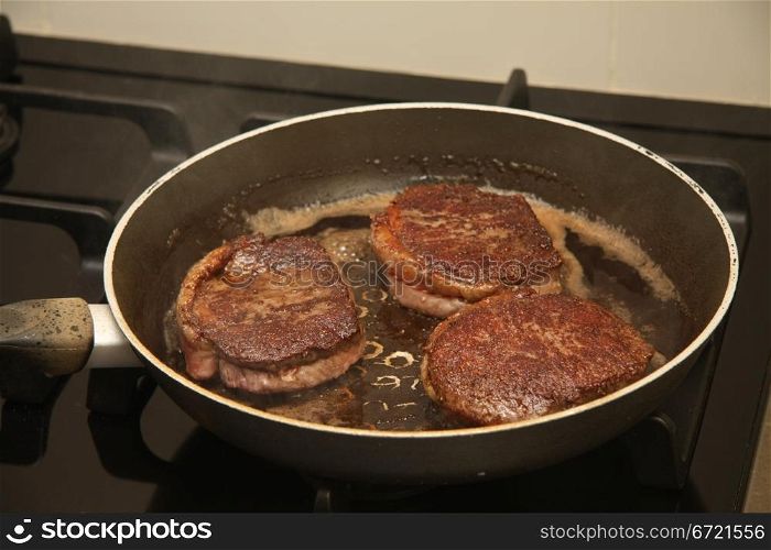 Three pieces of meat in a frying pan