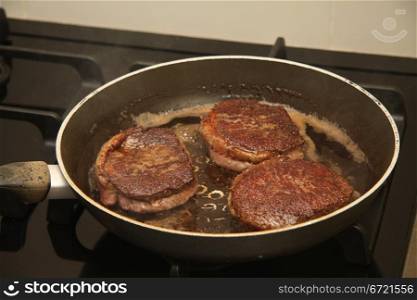 Three pieces of meat in a frying pan