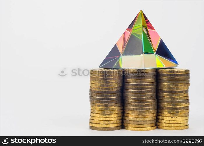 Three piles of coins, there is a glass pyramid on them, to the right is an empty space