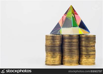 Three piles of coins, there is a glass pyramid on them, to the right is an empty space
