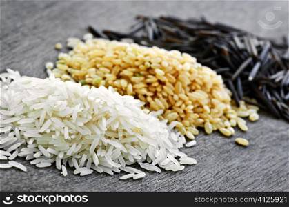Three piles of white, brown and wild black uncooked rice
