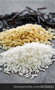 Three piles of white, brown and wild black uncooked rice