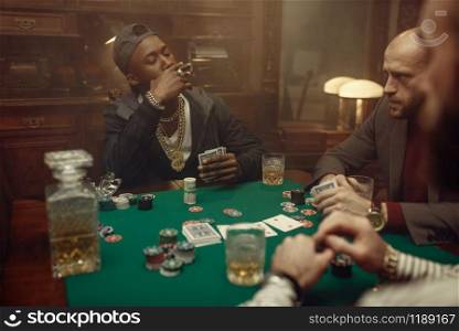 Three poker players sitting at gaming table with green cloth in casino. Games of chance addiction, gambling house. Men leisures with whiskey and cigars,. Poker players at gaming table with green cloth