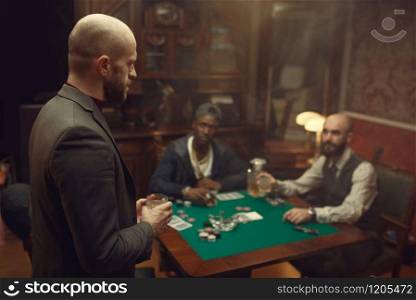 Three poker players with whiskey and cigars sitting at the table. Games of chance addiction, gambling house,