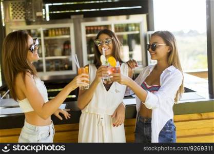 Three pretty young women drinking coctais and having fun in the beach bar