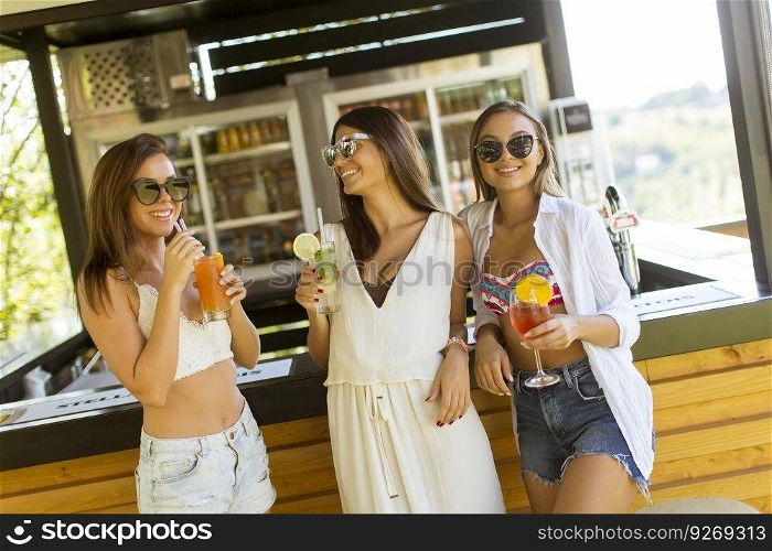 Three pretty young women drinking coctais and having fun in the beach bar