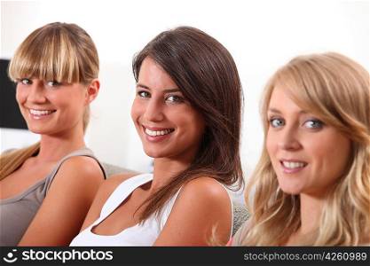 Three pretty young women sitting on a sofa