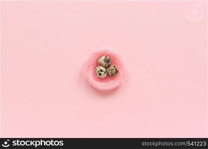 Three quail eggs in decorative pink nest in minimal style on pink paper background. Concept Happy Easter Greeting card Top view Copy space Template for lettering, text or your design.. Three quail eggs in decorative pink nest in minimal style on pink paper background. Concept Happy Easter Greeting card Top view Copy space Template for lettering, text or your design