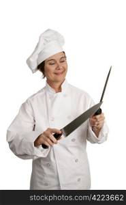 Three quarter view of a female chef sharpening knives. Isolated on white.