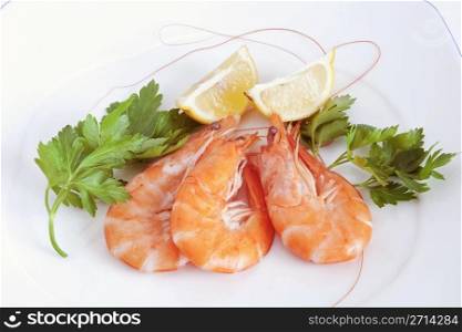 three raw prawns with lemon and parsley on a white plate