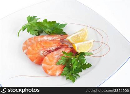 three raw prawns with lemon and parsley on a white plate isolated with clipping path