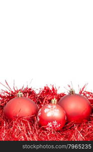 three red Christmas balls and tinsel isolated on white background