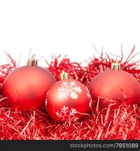 three red Christmas baubles and tinsel isolated on white background