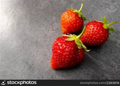 Three  red ripe strawberries over dark background with copy space. Three red ripe strawberries over dark