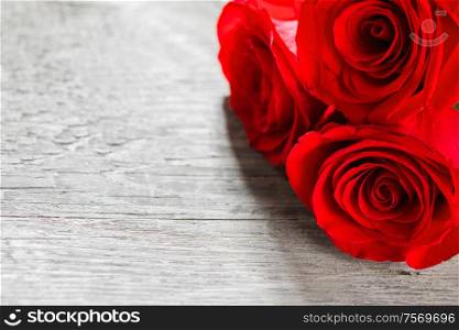 Three red roses on wooden background with copy space. Three red roses on wood