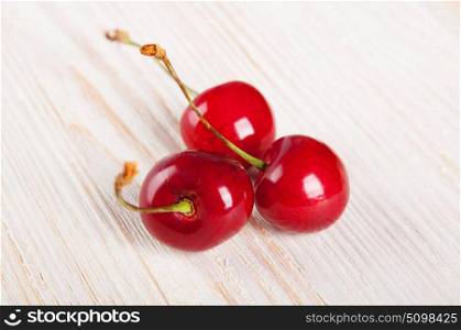 Three red sweet cherries on awooden background
