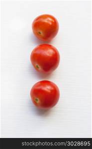 Three red tomatoes on a white .. Three red tomatoes on a white background.