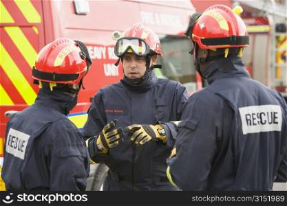 Three rescue workers talking by rescue vehicle