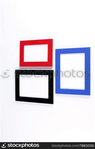 Three retro wooden photo frames, red, blue, black on white wall background.