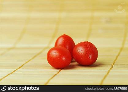 three ripe and juicy cherry tomatoes on bamboo napkin