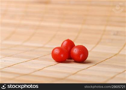 three ripe and juicy cherry tomatoes on bamboo napkin