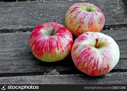 Three ripe apples on a rustic gray boards