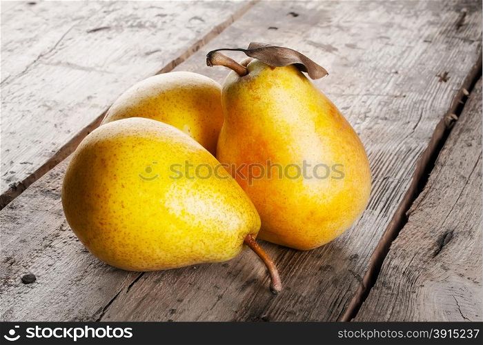 Three ripe juicy yellow pears on a wooden table