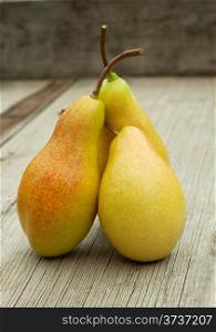 Three ripe pears with cuttings on a wooden background
